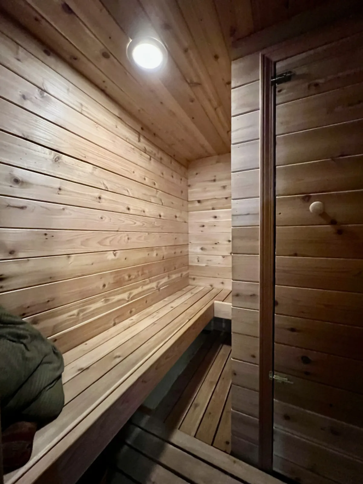 A tranquil cedar sauna featuring wooden benches, wood-paneled walls, and a soft ceiling light. The space exudes a peaceful, spa-like ambiance perfect for relaxation and rejuvenation after outdoor activities.