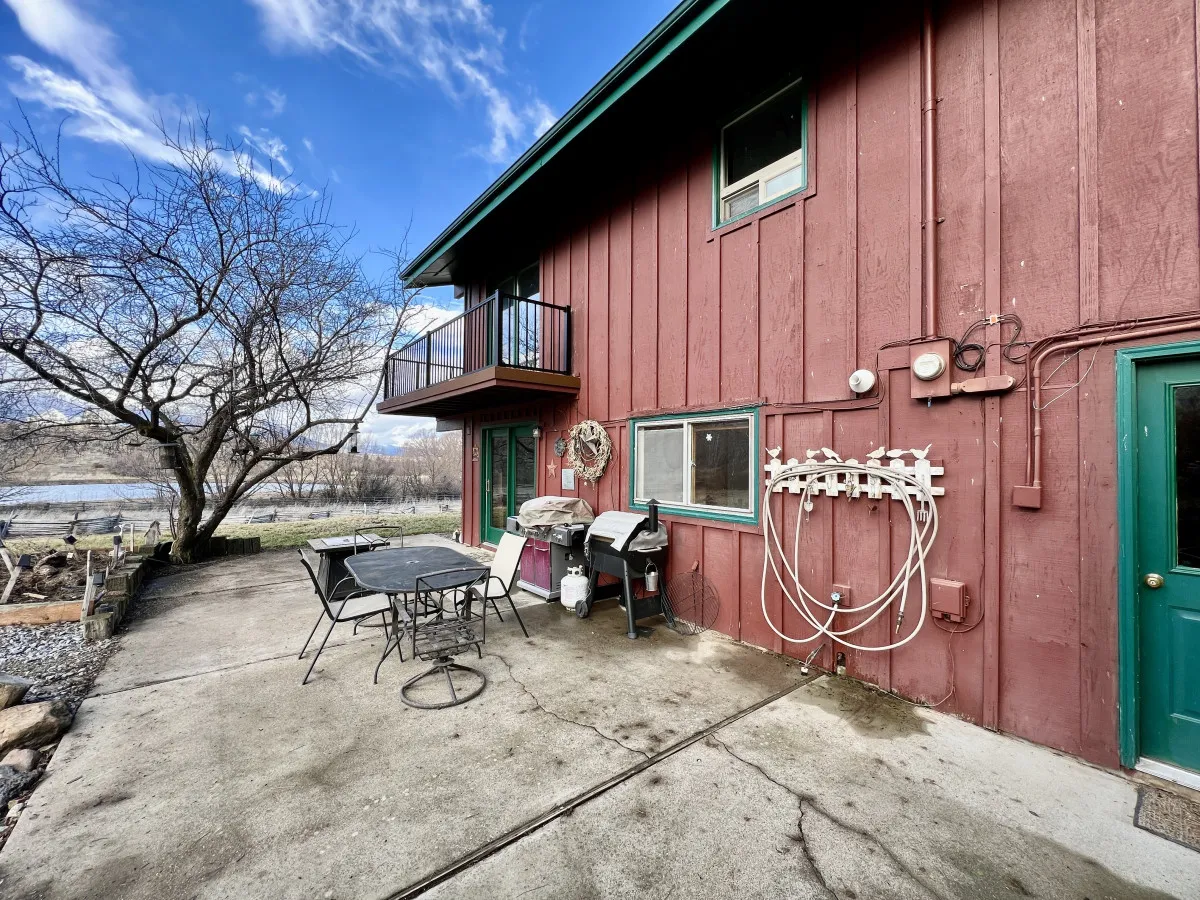A red wooden exterior with a spacious balcony features an outdoor dining set and BBQ grill. The grill is prominently visible, with enough space for guests to gather, eat, and enjoy the scenic views from the balcony.